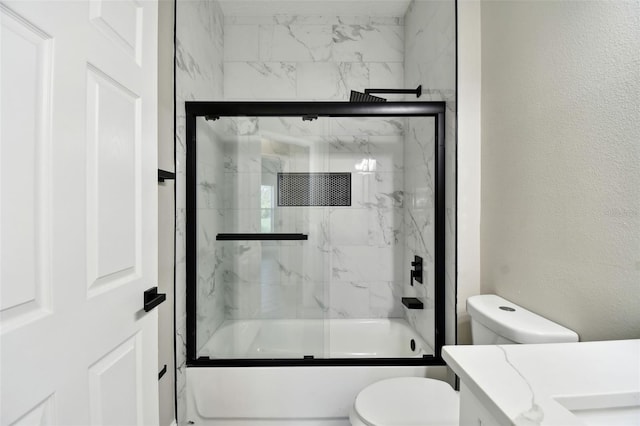 full bathroom featuring vanity, combined bath / shower with glass door, and toilet