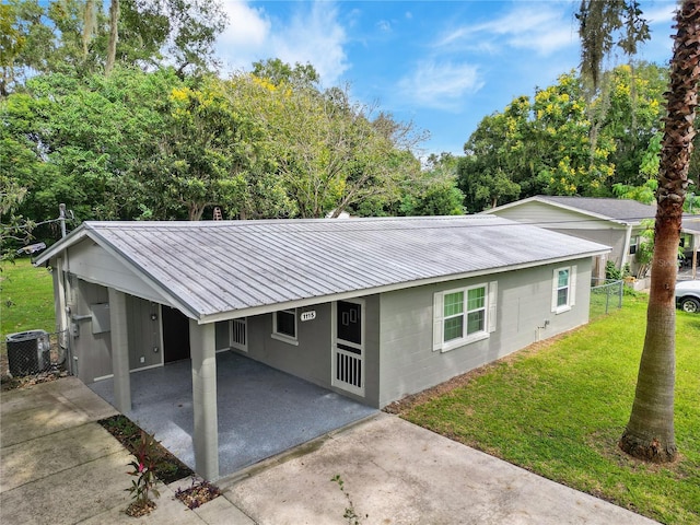 ranch-style home featuring central air condition unit, a front yard, and a carport