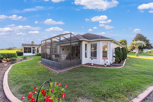 back of house with a lawn, glass enclosure, and a sunroom