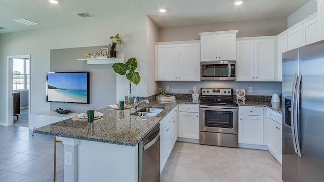 kitchen featuring kitchen peninsula, appliances with stainless steel finishes, sink, and white cabinetry