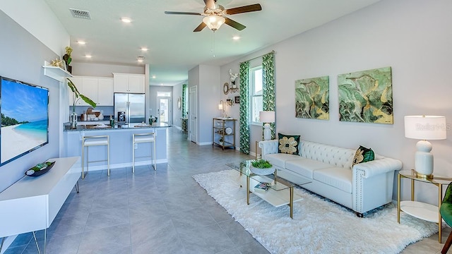 living room with ceiling fan and dark tile patterned flooring