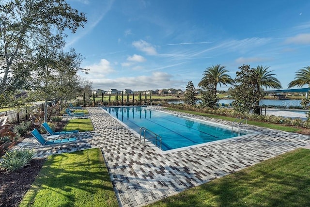 view of swimming pool with a water view and a lawn