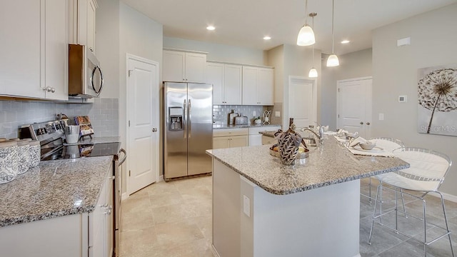 kitchen featuring a kitchen island with sink, pendant lighting, a breakfast bar, stainless steel appliances, and white cabinets