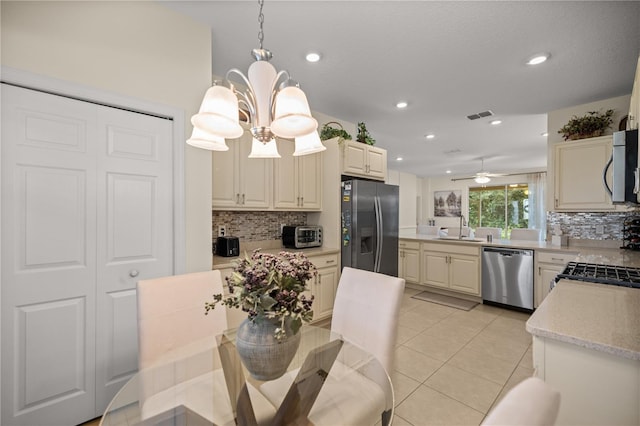 kitchen with sink, backsplash, decorative light fixtures, ceiling fan with notable chandelier, and appliances with stainless steel finishes