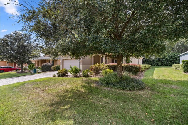 view of property hidden behind natural elements featuring a front lawn and a garage