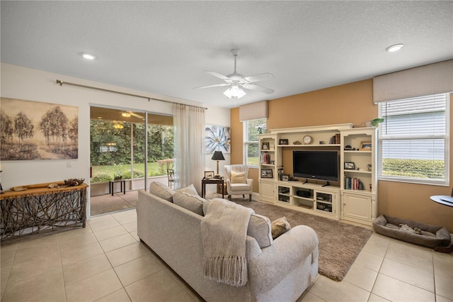 living room featuring a textured ceiling, ceiling fan, a healthy amount of sunlight, and light tile patterned flooring