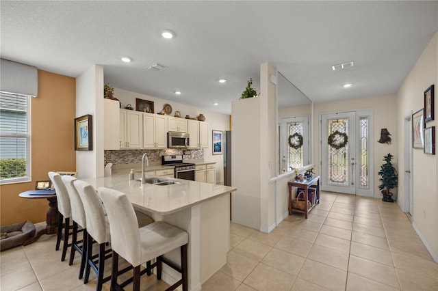 kitchen with sink, a kitchen breakfast bar, kitchen peninsula, light tile patterned floors, and appliances with stainless steel finishes