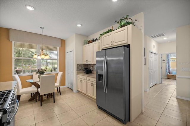 kitchen featuring hanging light fixtures, tasteful backsplash, a chandelier, light tile patterned floors, and appliances with stainless steel finishes