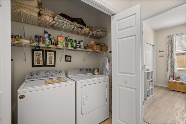 laundry area with washing machine and dryer and light hardwood / wood-style flooring