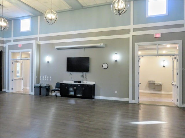 living room with dark hardwood / wood-style flooring, a towering ceiling, and a notable chandelier