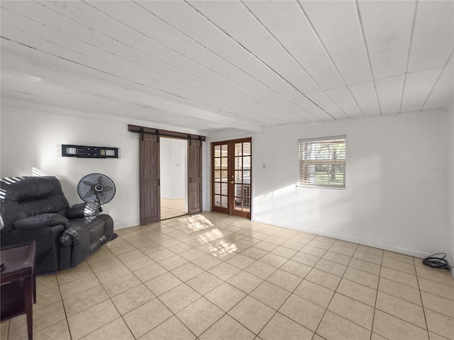 unfurnished living room featuring french doors, light tile patterned flooring, and a barn door