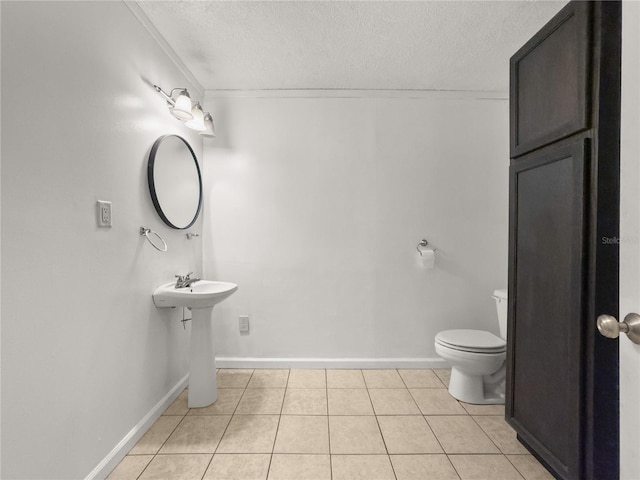 bathroom featuring toilet, tile patterned floors, a textured ceiling, and ornamental molding