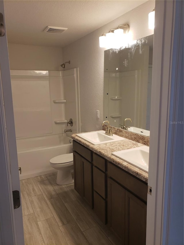 full bathroom featuring toilet, shower / washtub combination, a textured ceiling, and vanity