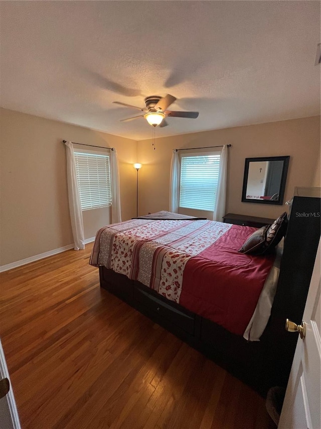 bedroom with ceiling fan, hardwood / wood-style floors, and a textured ceiling