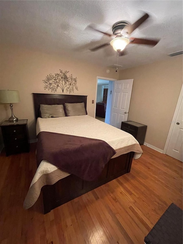 bedroom featuring hardwood / wood-style flooring, ceiling fan, and a textured ceiling