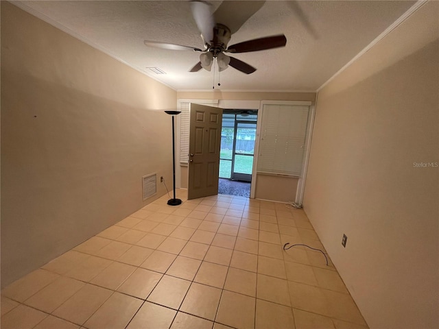 empty room featuring a textured ceiling, crown molding, light tile patterned floors, and ceiling fan