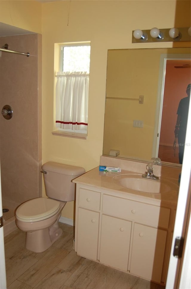 bathroom featuring vanity, wood-type flooring, toilet, and walk in shower