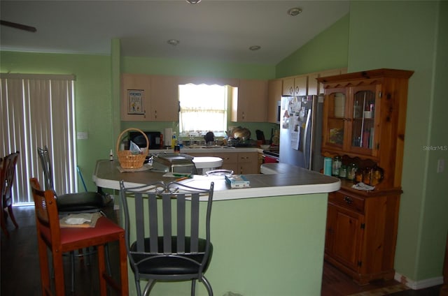 kitchen featuring lofted ceiling, a kitchen island, wood-type flooring, stainless steel fridge, and sink