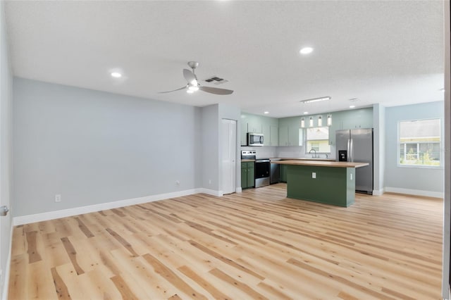 kitchen featuring a kitchen island, light wood-type flooring, stainless steel appliances, sink, and green cabinets