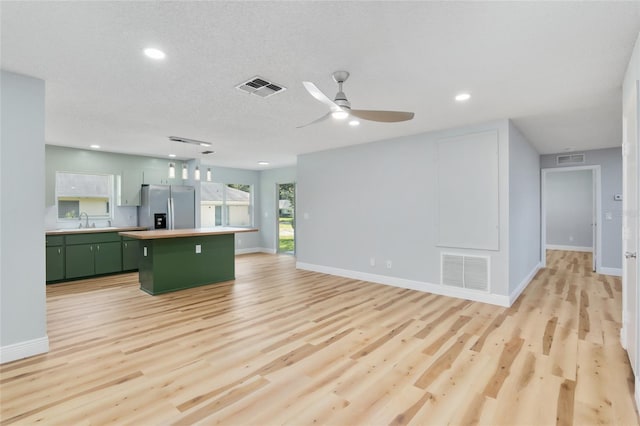 kitchen with sink, a kitchen island, green cabinetry, light hardwood / wood-style flooring, and stainless steel fridge with ice dispenser