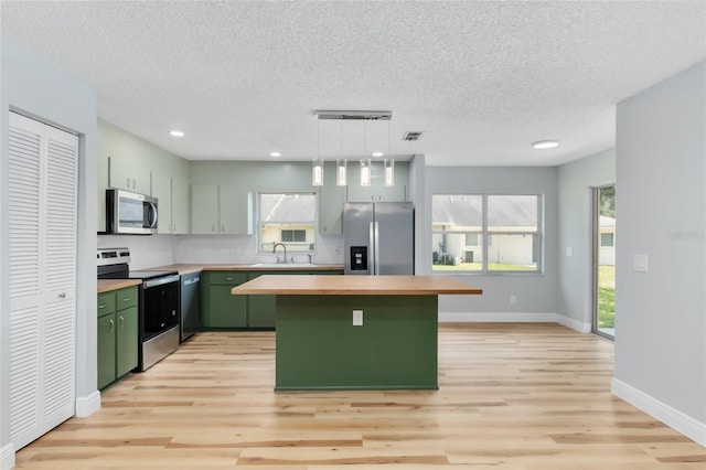 kitchen featuring decorative light fixtures, appliances with stainless steel finishes, plenty of natural light, and green cabinets