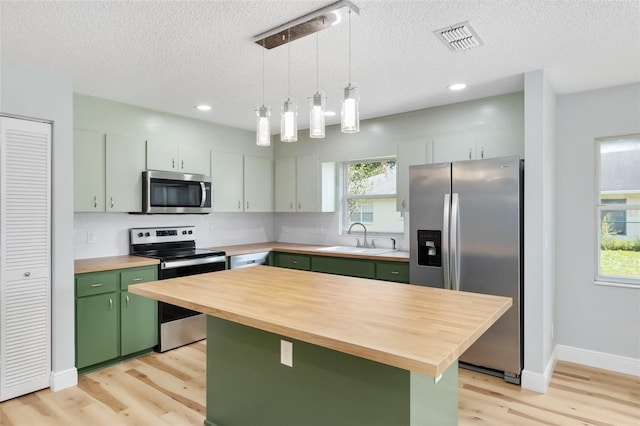 kitchen featuring pendant lighting, sink, a kitchen island, green cabinetry, and stainless steel appliances