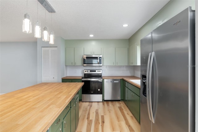 kitchen with green cabinetry, wooden counters, decorative light fixtures, and stainless steel appliances