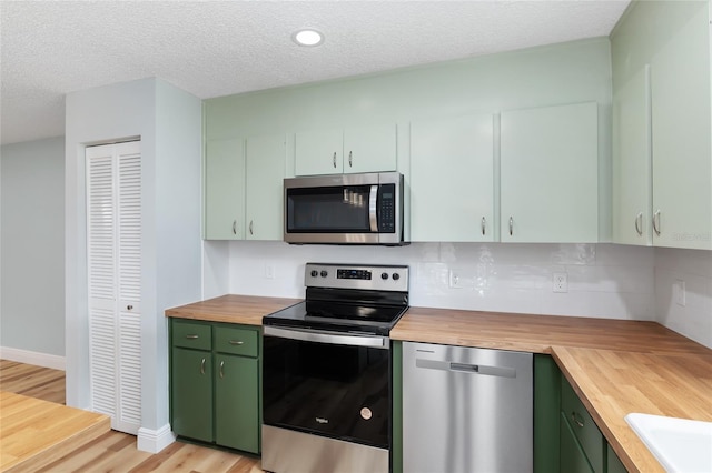 kitchen with green cabinetry, stainless steel appliances, light hardwood / wood-style floors, and wooden counters