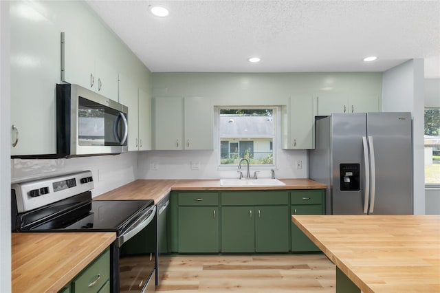 kitchen with green cabinetry, stainless steel appliances, plenty of natural light, and sink