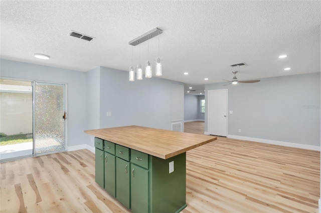 kitchen with wooden counters, green cabinetry, light hardwood / wood-style flooring, decorative light fixtures, and a center island