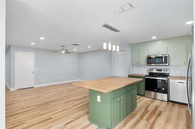 kitchen featuring appliances with stainless steel finishes, a center island, green cabinets, light hardwood / wood-style floors, and butcher block counters