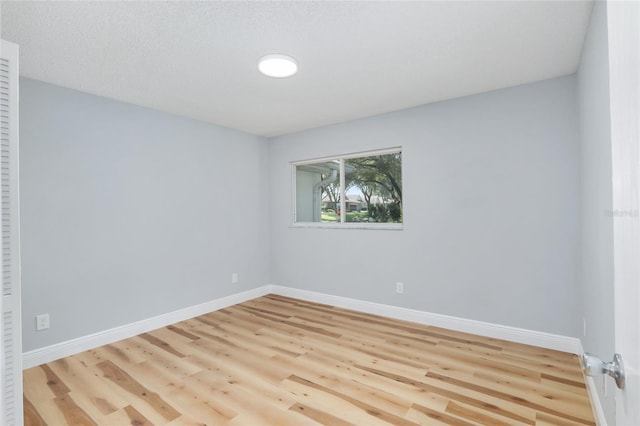 unfurnished room with a textured ceiling and light wood-type flooring