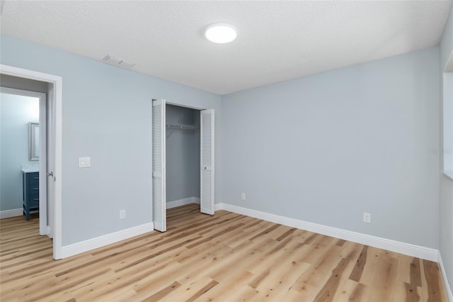 unfurnished bedroom with a closet, light hardwood / wood-style flooring, and a textured ceiling