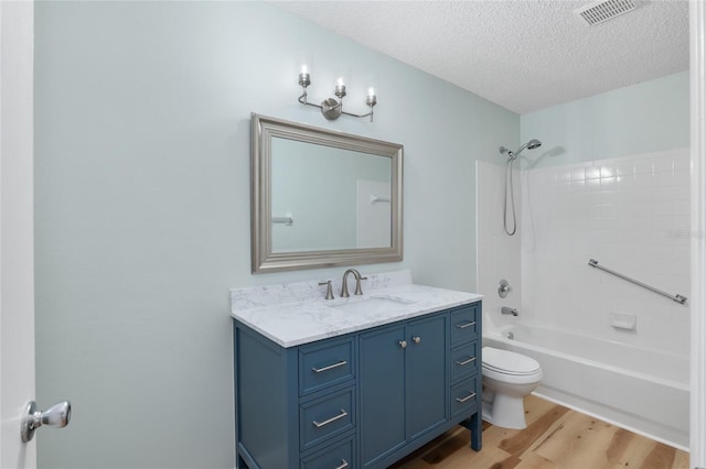 full bathroom featuring hardwood / wood-style floors, vanity, bathtub / shower combination, toilet, and a textured ceiling