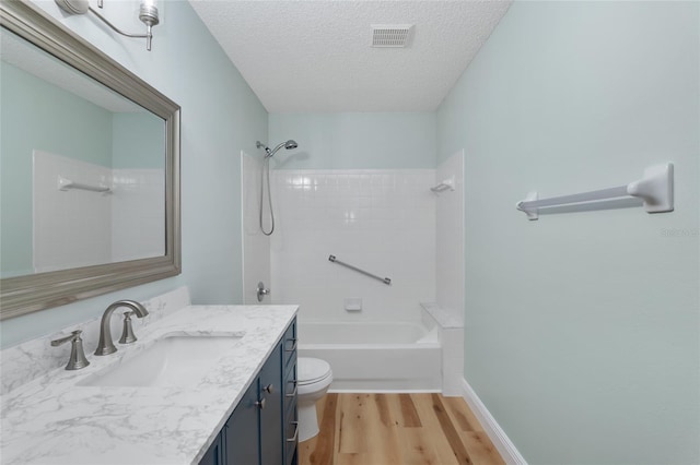 full bathroom featuring vanity, tiled shower / bath combo, wood-type flooring, a textured ceiling, and toilet