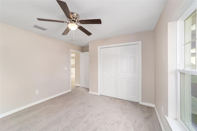 unfurnished bedroom with ceiling fan, a closet, light carpet, and multiple windows