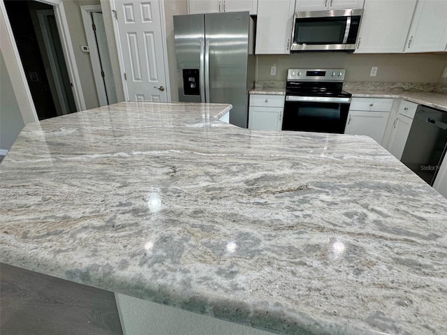 kitchen featuring light stone countertops, white cabinets, and stainless steel appliances