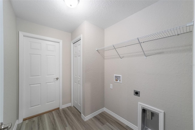 clothes washing area with light hardwood / wood-style floors, washer hookup, a textured ceiling, and hookup for an electric dryer