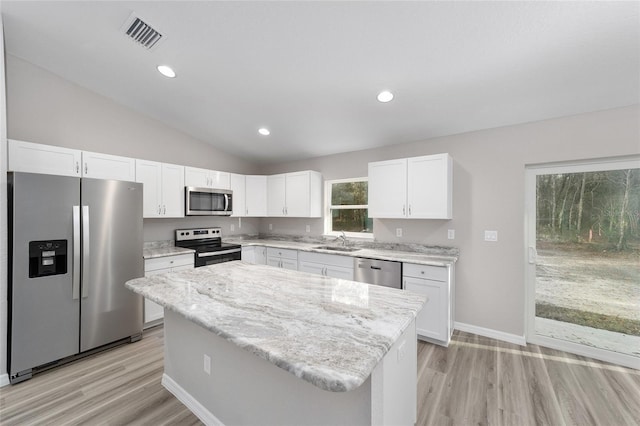 kitchen with vaulted ceiling, a center island, sink, appliances with stainless steel finishes, and white cabinets