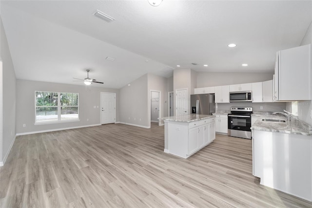 kitchen with appliances with stainless steel finishes, a kitchen island, white cabinetry, sink, and ceiling fan