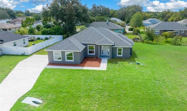 view of front facade featuring concrete driveway, a front lawn, fence, and a residential view