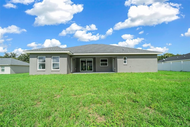 rear view of house featuring a yard, stucco siding, and fence