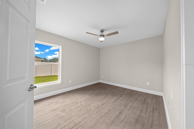 spare room featuring ceiling fan, baseboards, and wood finished floors