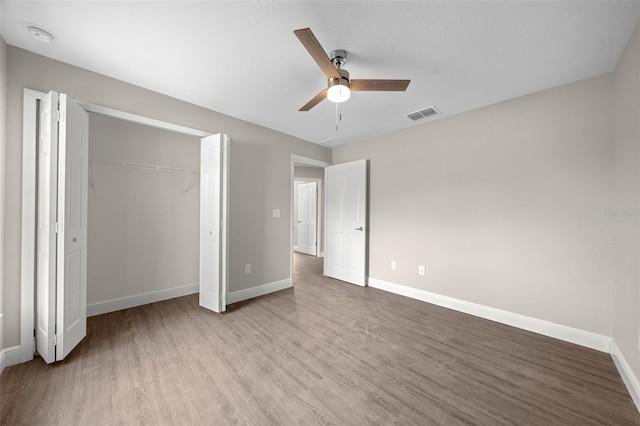 unfurnished bedroom with baseboards, wood finished floors, visible vents, and a closet