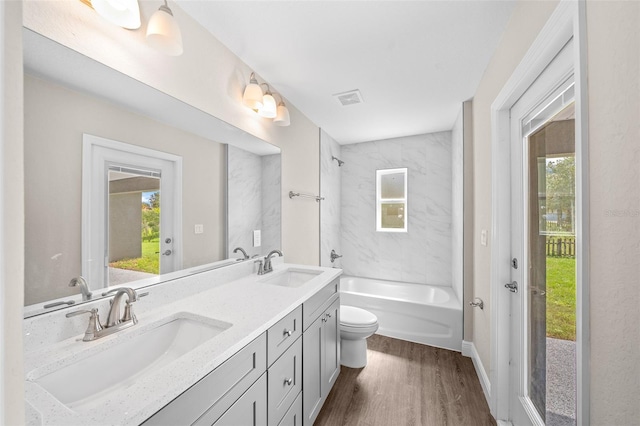 full bathroom featuring vanity, toilet, hardwood / wood-style flooring, and tiled shower / bath