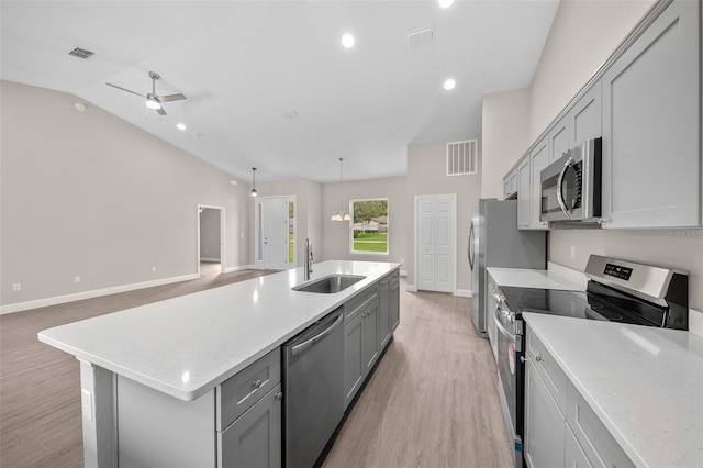 kitchen featuring appliances with stainless steel finishes, sink, light wood-type flooring, an island with sink, and lofted ceiling