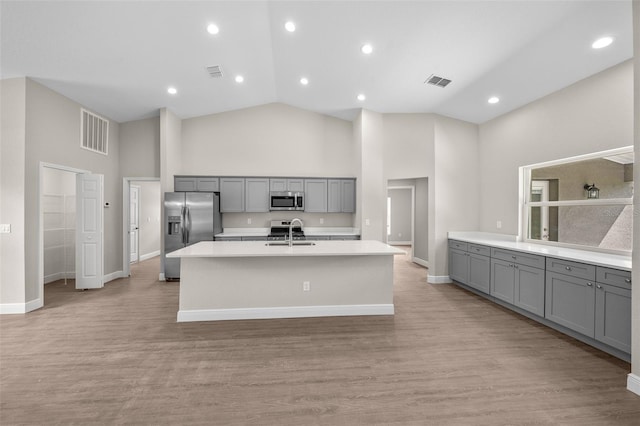 kitchen with high vaulted ceiling, stainless steel appliances, sink, and light wood-type flooring