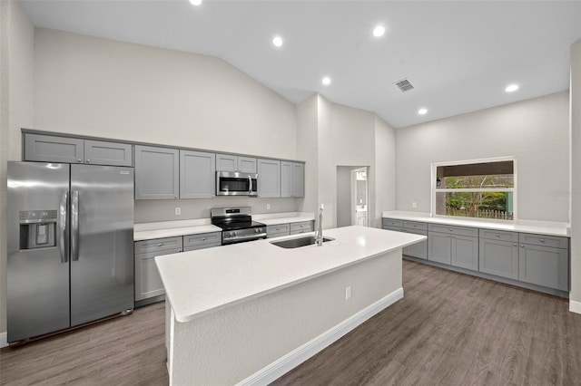 kitchen featuring hardwood / wood-style floors, stainless steel appliances, sink, and an island with sink