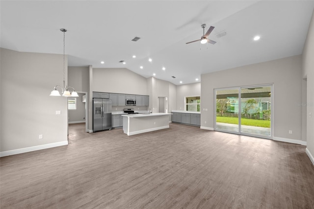 kitchen with gray cabinets, open floor plan, stainless steel appliances, and high vaulted ceiling