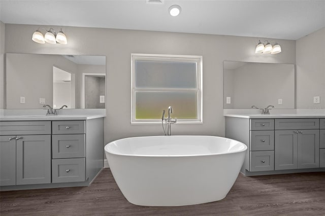full bathroom with a soaking tub, wood finished floors, and a sink